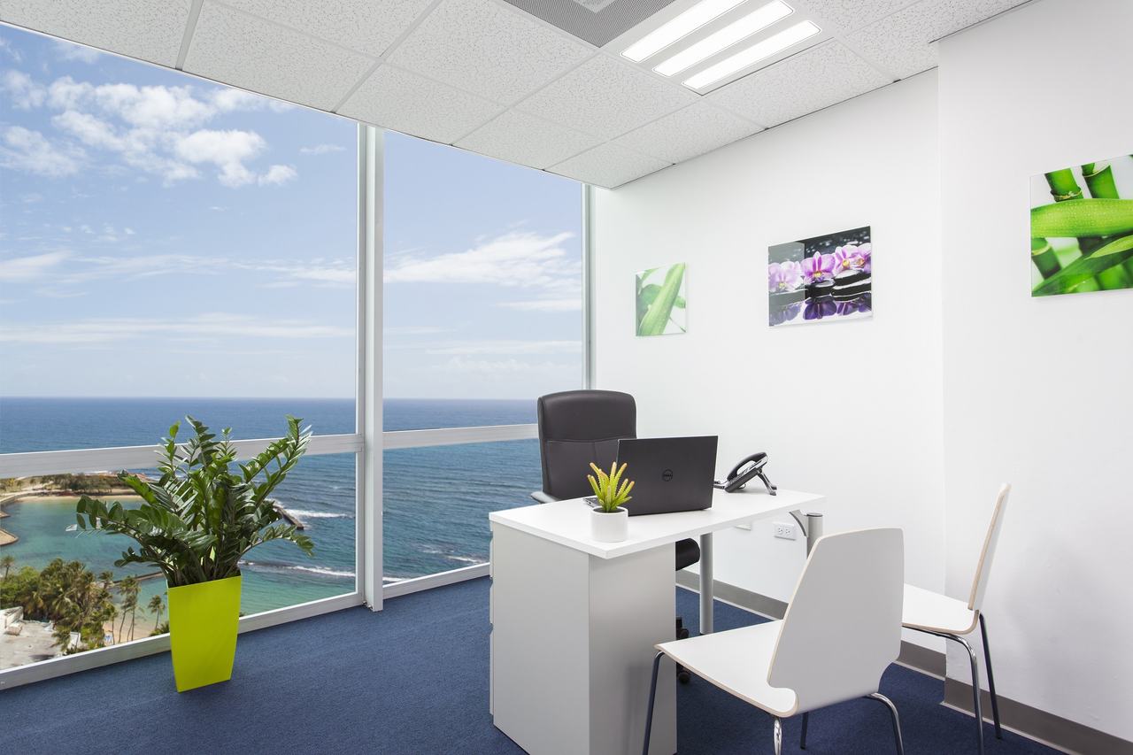 Private office with floor-to-ceiling windows overlooking the ocean and beach
